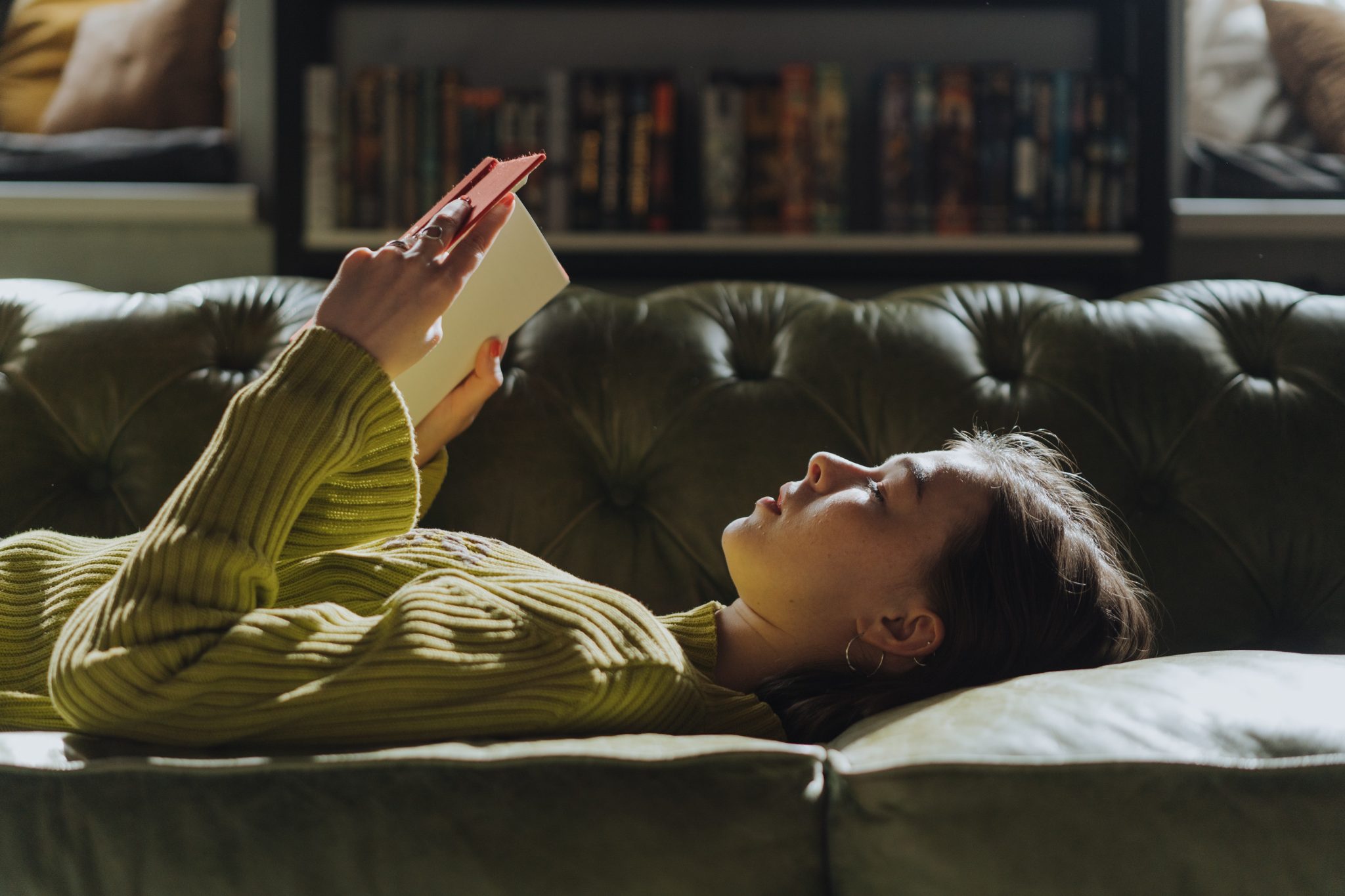femme qui lit un livre allongée sur son canapé