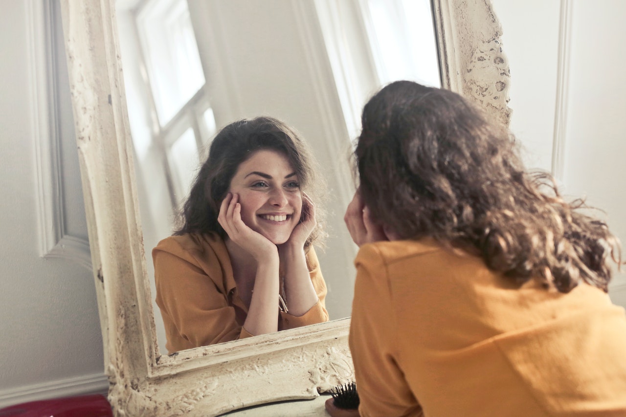 femme qui se regarde dans la miroir et se sourit